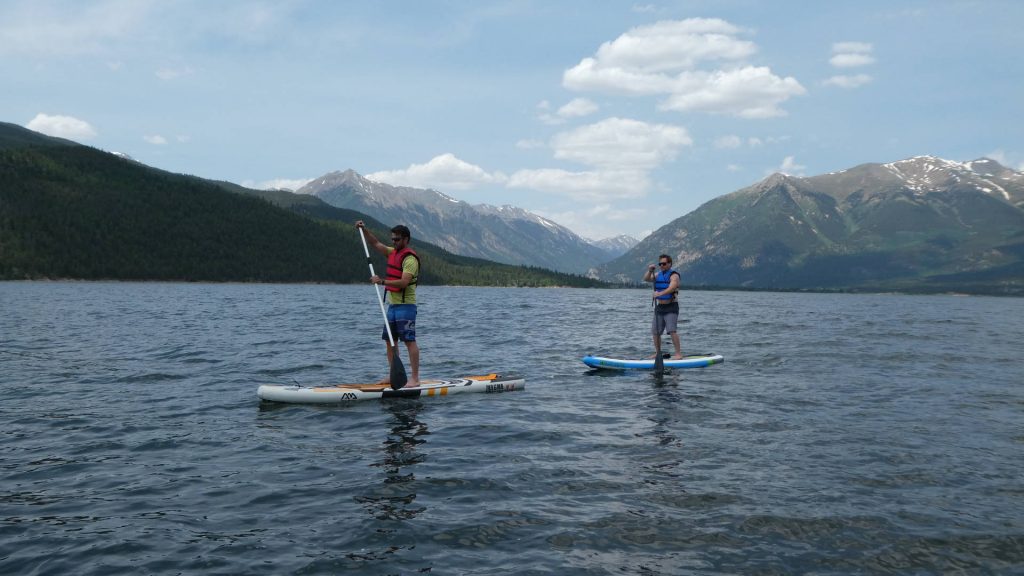 Two paddleboarders with pass in background
